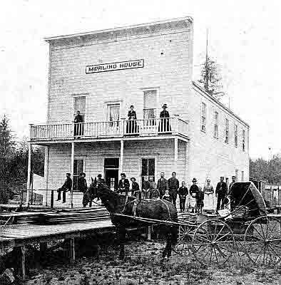 Tall two-story frame building, 'Morling House' sign in center of false front.